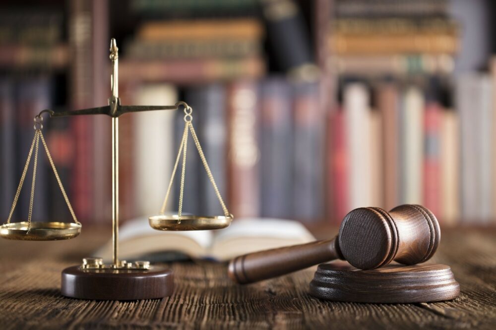 A balanced scale and a gavel representing risk advisory consulting services in a legal setting with blurred books in the background