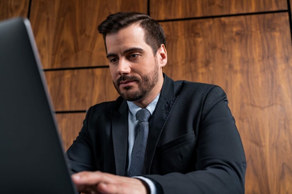 A professional in a business suit working on a laptop, reflecting financial reporting and accounting consultancy