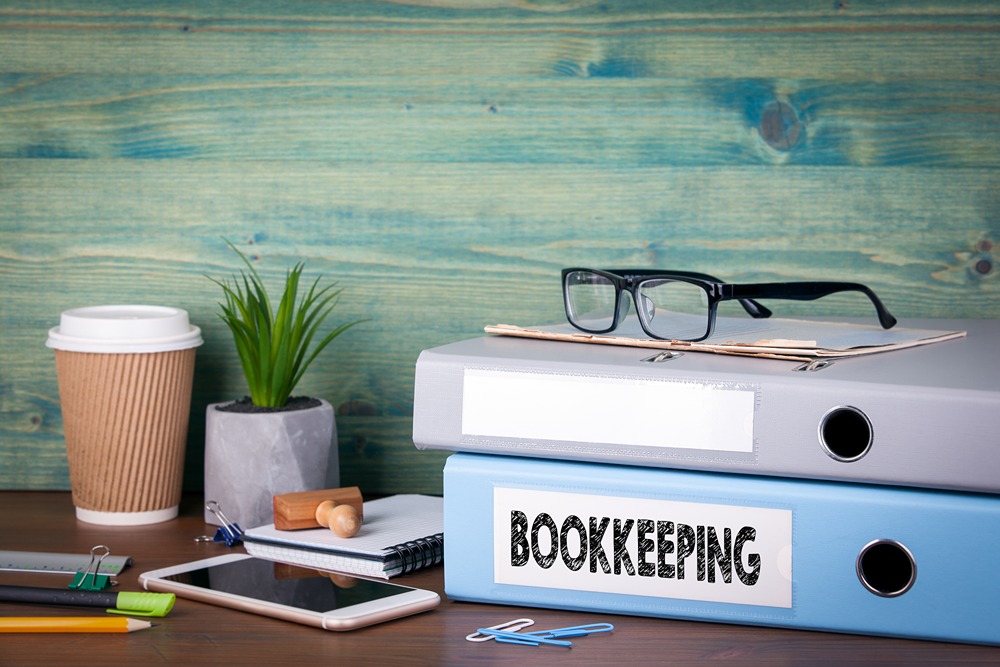 Desk with binders labeled 'BOOKKEEPING' and office supplies, representing organized bookkeeping services UAE for financial record-keeping