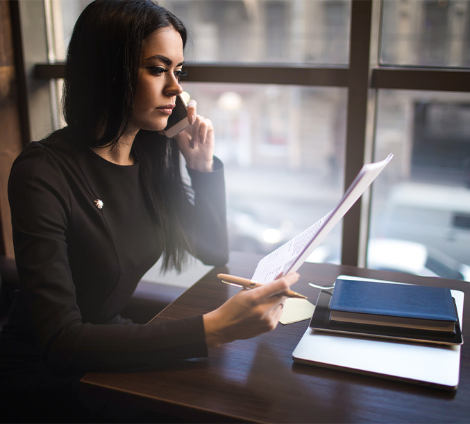Professional woman in a modern office reviewing a document while talking on the phone
