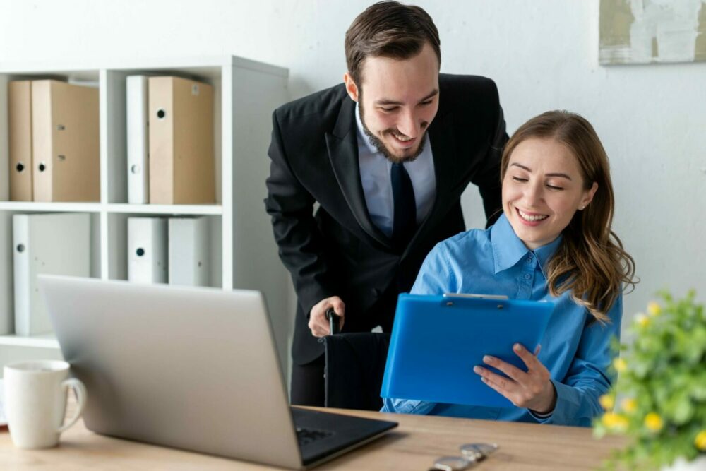 Two professionals reviewing a document together with smiles in an office setting